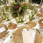 vasos de cristal verdes, flores violetas y mantel beige